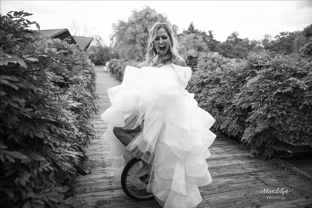 The bride in her wedding dress riding a unicycle. 